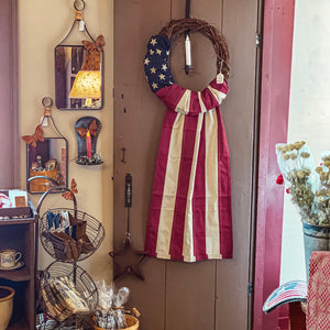 Our popular patriotic Flag Wreath available in tea stained stripes or natural white stripes -  hand wrapped around a grapevine wreath with a 100% cotton banner flag